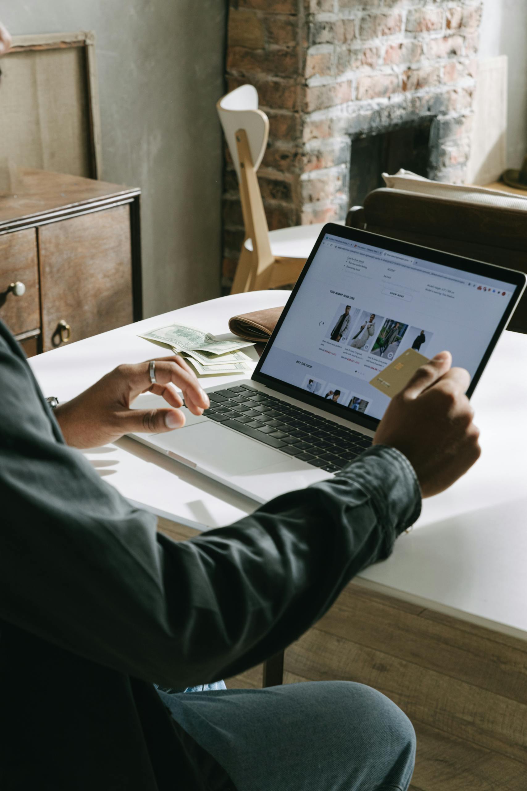 An adult uses a credit card for online shopping on a laptop indoors.